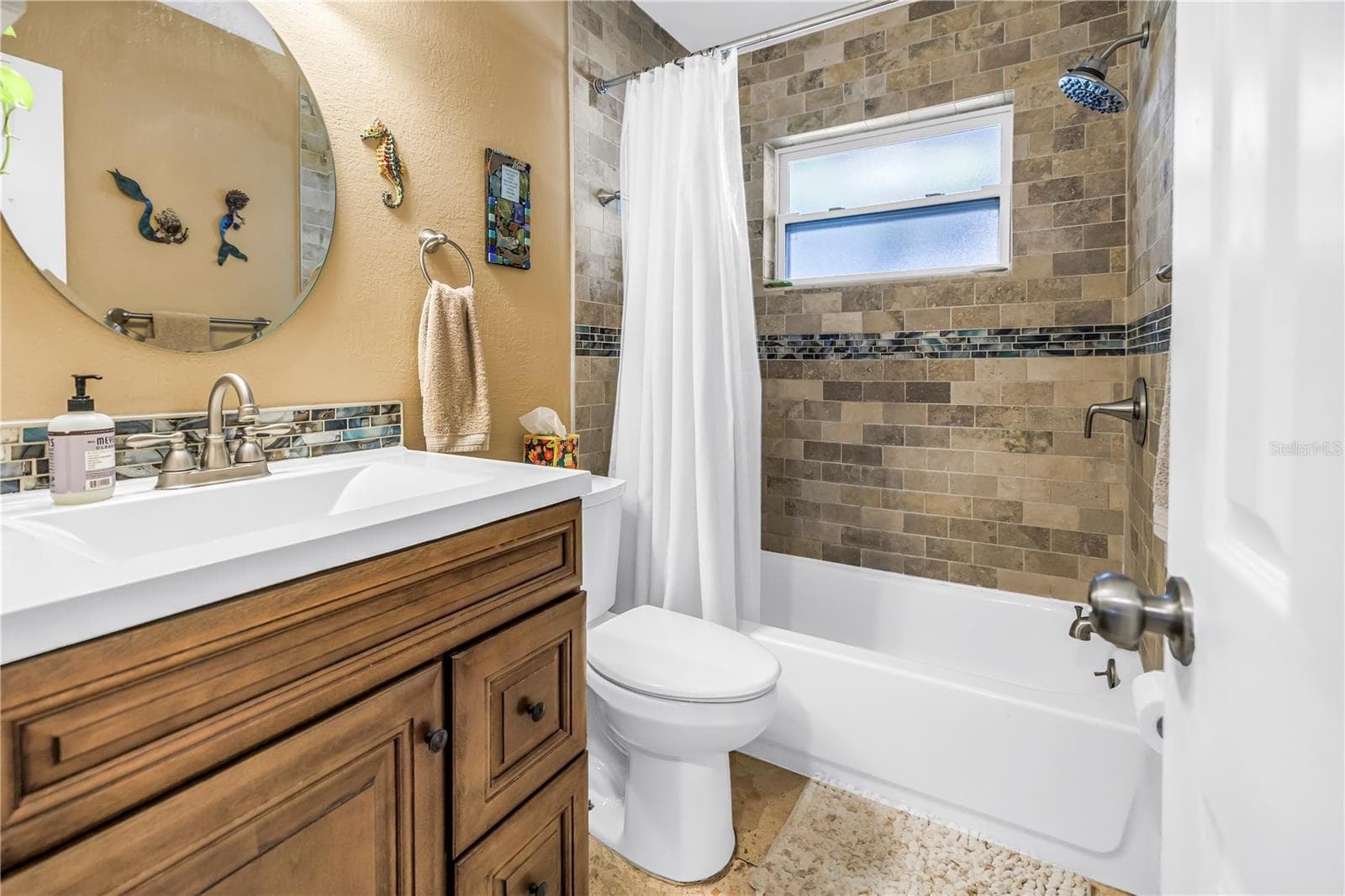 Bathroom featuring travertine, a bathtub with shower and a brand new window. - 2573 62ND TER N, ST PETERSBURG