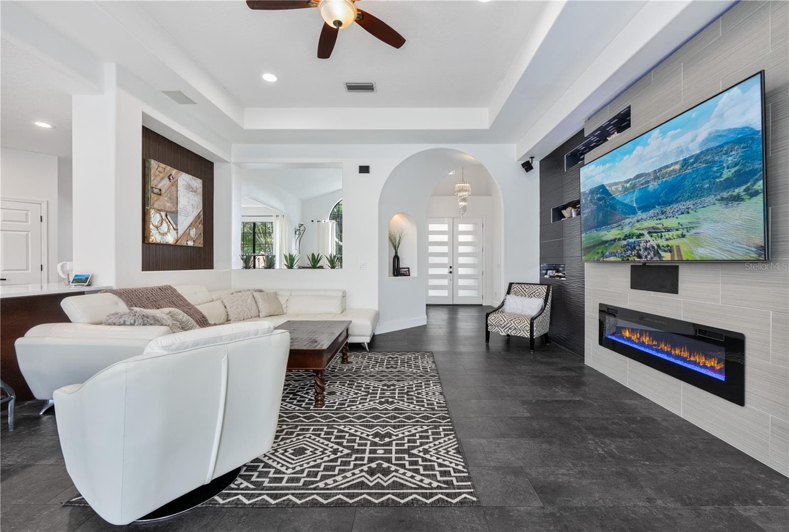 Spacious family room featuring custom wall treatments, recessed display niches with LED lighting and decorative mosaic tile, and a cozy fireplace. - 1854 VISTA ROYALE BLVD, ORLANDO