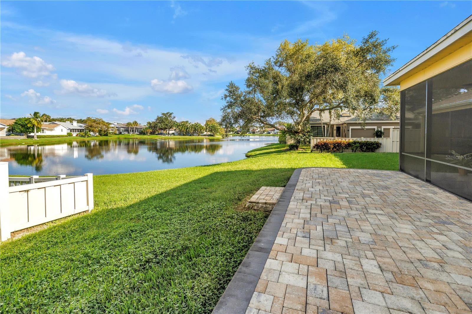 The elevated paver patio at the rear of the property overlooks a scenic grassy knoll and provides an expansive view of the lake, which serves as a natural habitat for various tropical birds. - 868 GLADES CT NE, ST PETERSBURG
