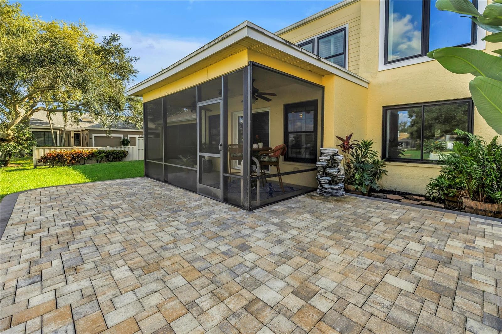 This screened, covered patio features a raised paver deck, providing an ideal space for an outdoor kitchen or grill.  Adirondacks ?! - 868 GLADES CT NE, ST PETERSBURG