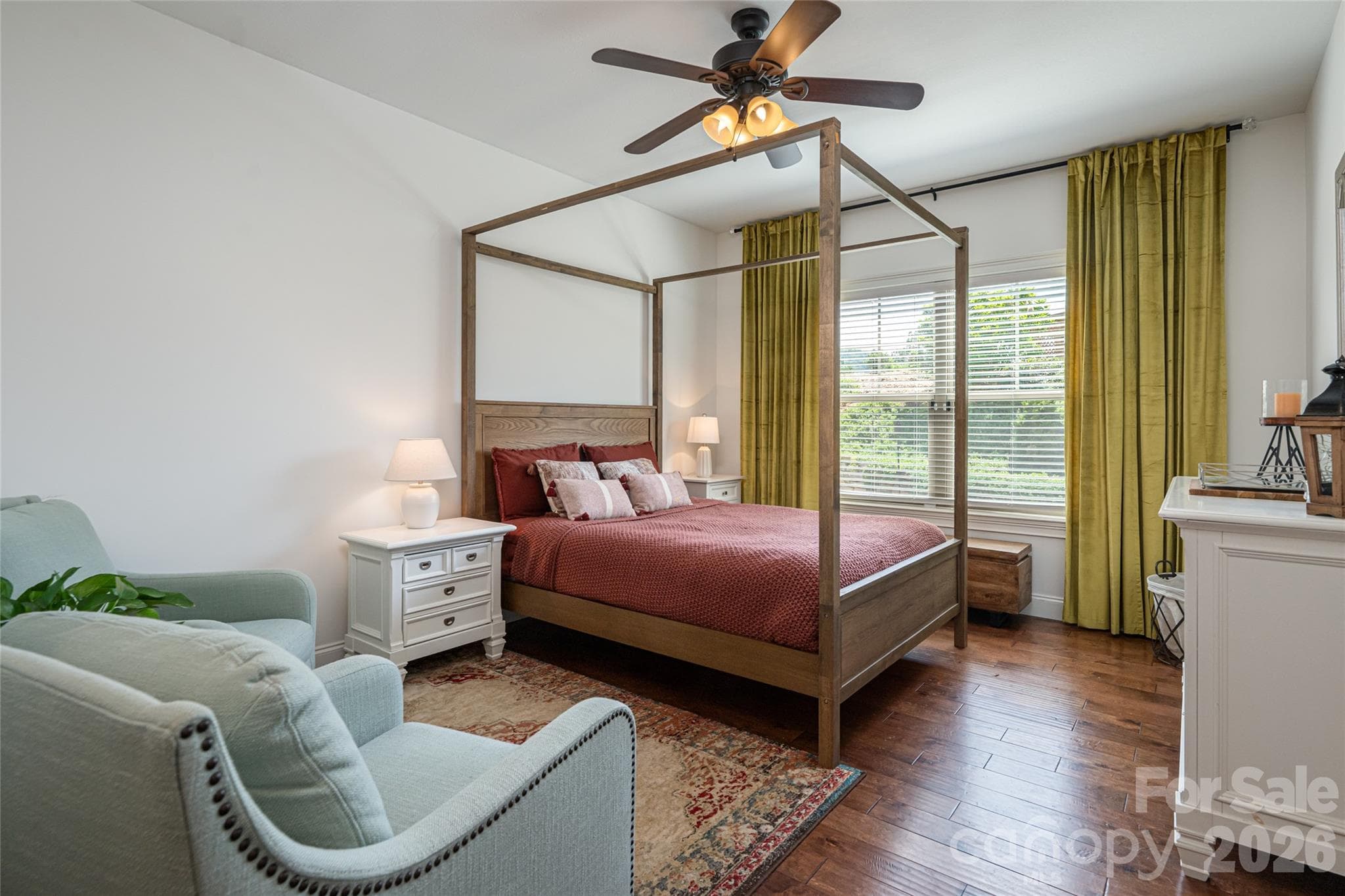 Main-level primary suite with ceiling fan, wood floors, and windows on two walls. - 17 Asher Lane, Arden