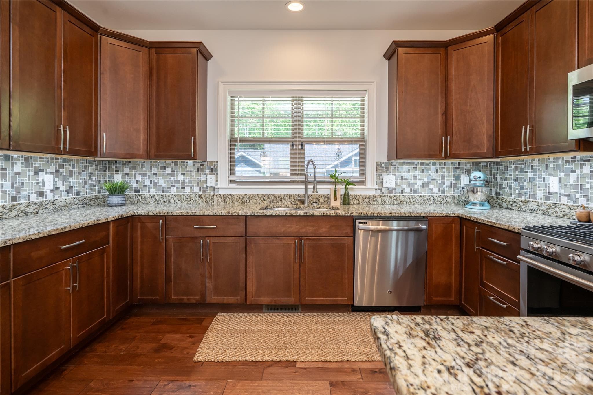 Wide kitchen view showing glass-tile backsplash, under-cabinet lighting, and generous counter space. - 17 Asher Lane, Arden