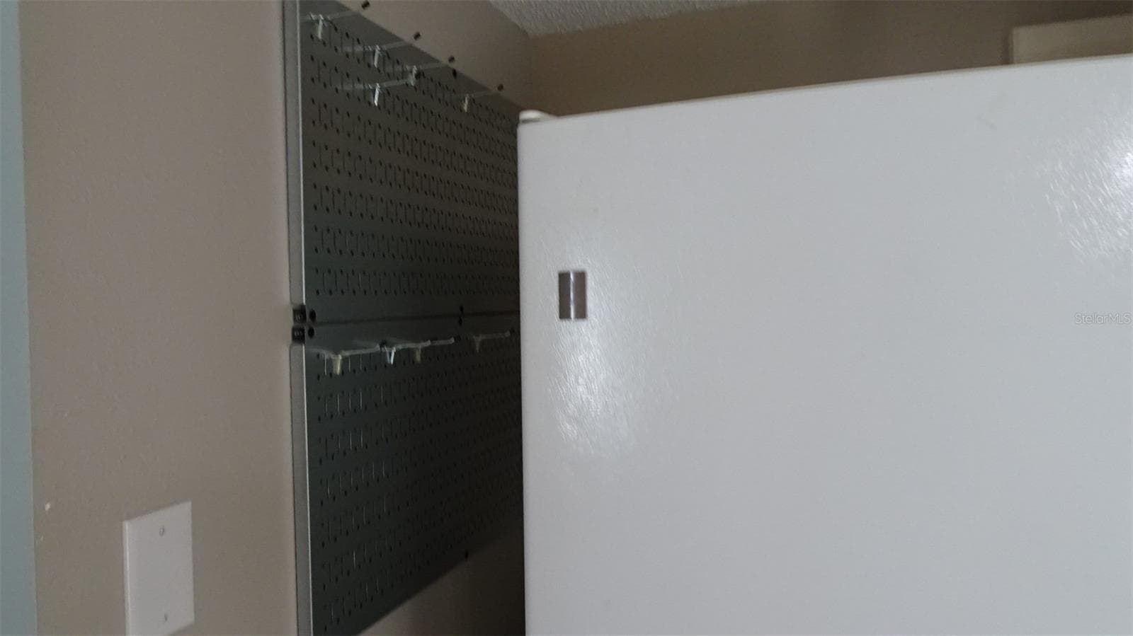 Pegboard with hooks next to refrigerator for pots and pans and whatnots. - 7800 38TH TER N, ST PETERSBURG