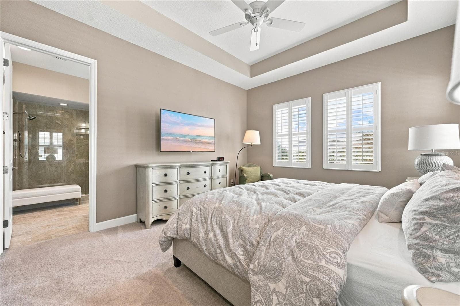 spacious primary suite, featuring an elegant tray ceiling and two walk-in closets for ample storage. - 291 COMPASS POINT DR #201, BRADENTON