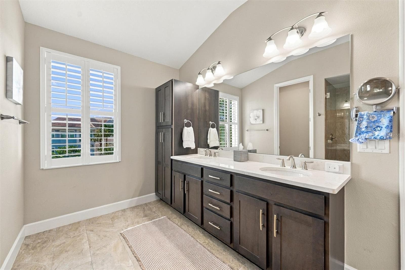 The spacious primary ensuite features dual vanities, a large walk-in shower, a private water closet, and convenient access to one of the suite’s two walk-in closets. - 291 COMPASS POINT DR #201, BRADENTON