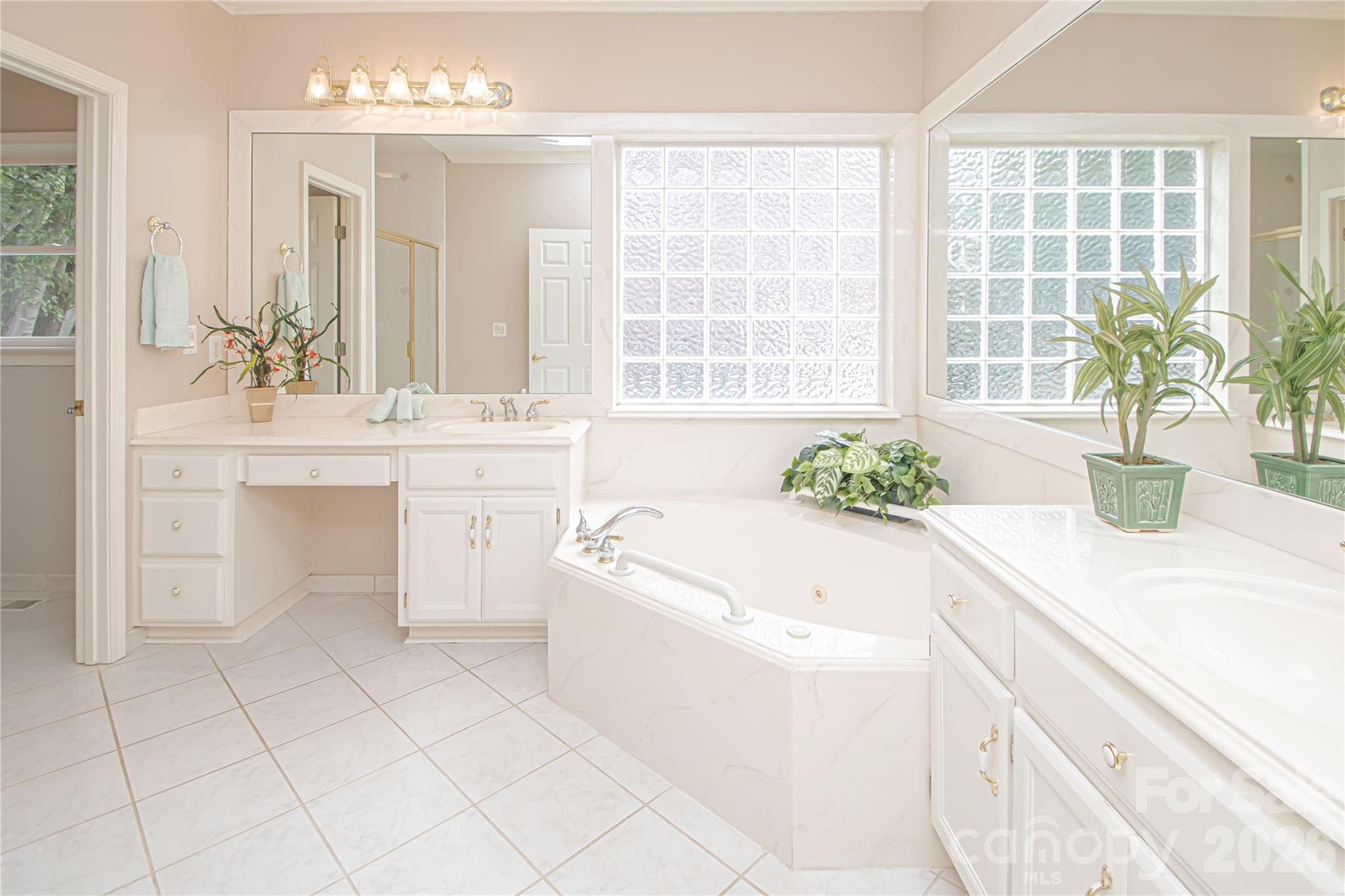 PRIMARY BATHROOM 10'x15': white tiled floors, glass ceiling light fixture, jet spray garden tub, Tide Block insulated glass tile "window", crown molding, updated light fixtures and custom framed mirrors, - 5480 Glen Forest Drive, Charlotte