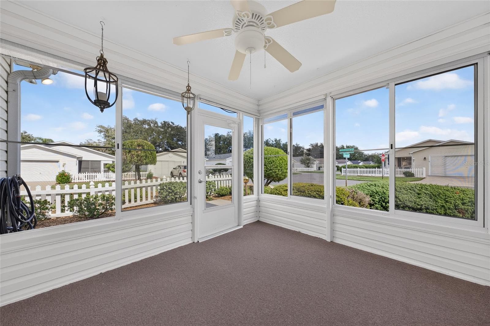 ENCLOSED LANAI - Plexiglass windows surround a bright sitting area with a ceiling fan and offers views of the landscaping and the corner of Escobar Ave & Elana Place. - 2124 ESCOBAR AVE, THE VILLAGES