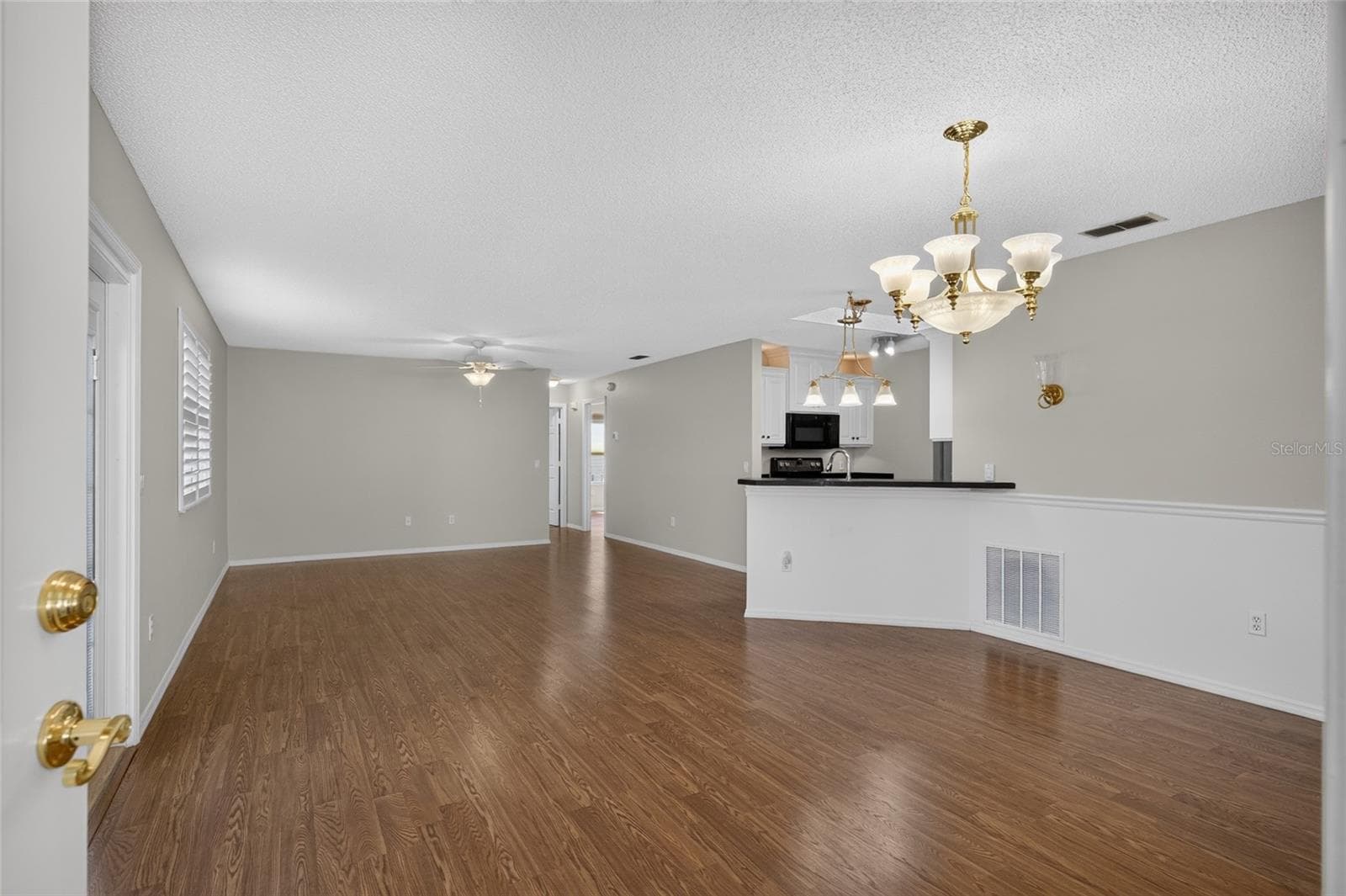 View from FRONT DOOR - Shows DINING ROOM (front R), KITCHEN w/ breakfast bar (center R), LIVING ROOM (back L), and HALLWAY (back R) to rear of villa. - 2124 ESCOBAR AVE, THE VILLAGES