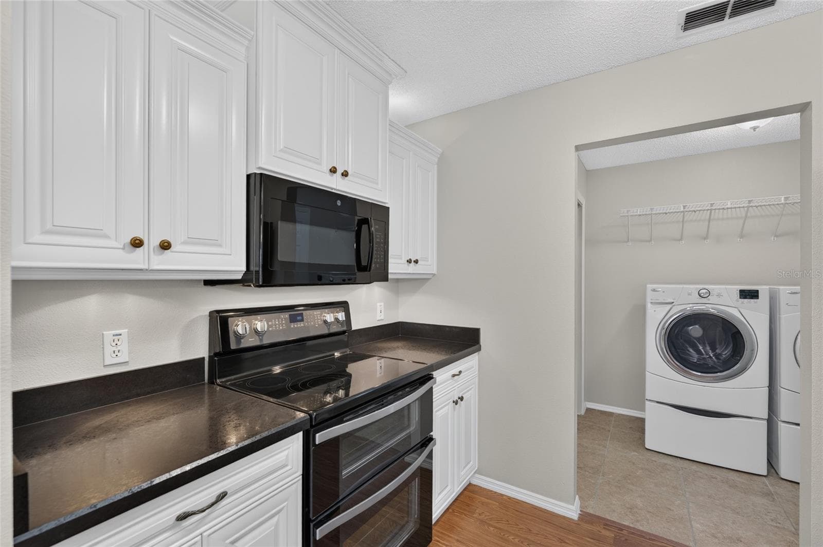 KITCHEN -View of a DOUBLE OVEN and OTC MICROWAVE HOOD which are located on the south wall of the kitchen. INDOOR LAUNDRY is visible on R. - 2124 ESCOBAR AVE, THE VILLAGES