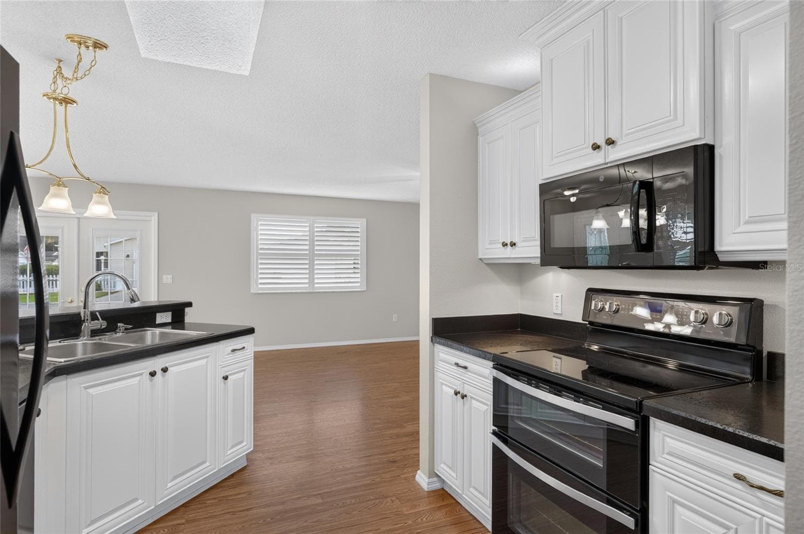 KITCHEN - SKYLIGHT brings natural light into the workspace, with a view through to the living/dining area. - 2124 ESCOBAR AVE, THE VILLAGES