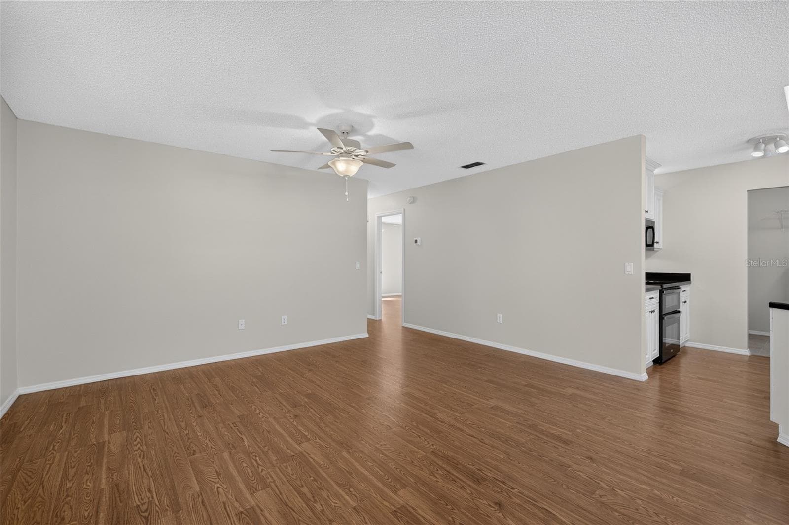 LIVING ROOM - WOOD-LOOK LAMINATE flooring in the main living area, KITCHEN visible on R. - 2124 ESCOBAR AVE, THE VILLAGES