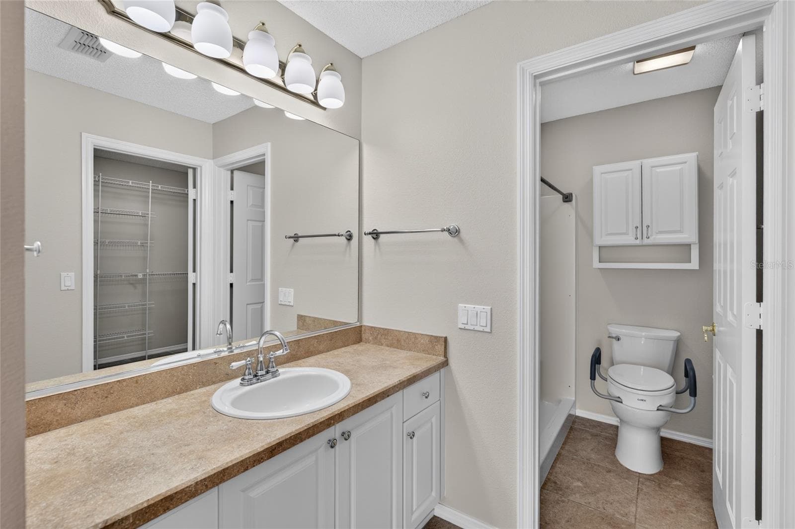 PRIMARY ENSUITE BATHROOM - View of separate comfort height toilet & WALK-IN SHOWER. Note wall cabinet above the toilet. - 2124 ESCOBAR AVE, THE VILLAGES