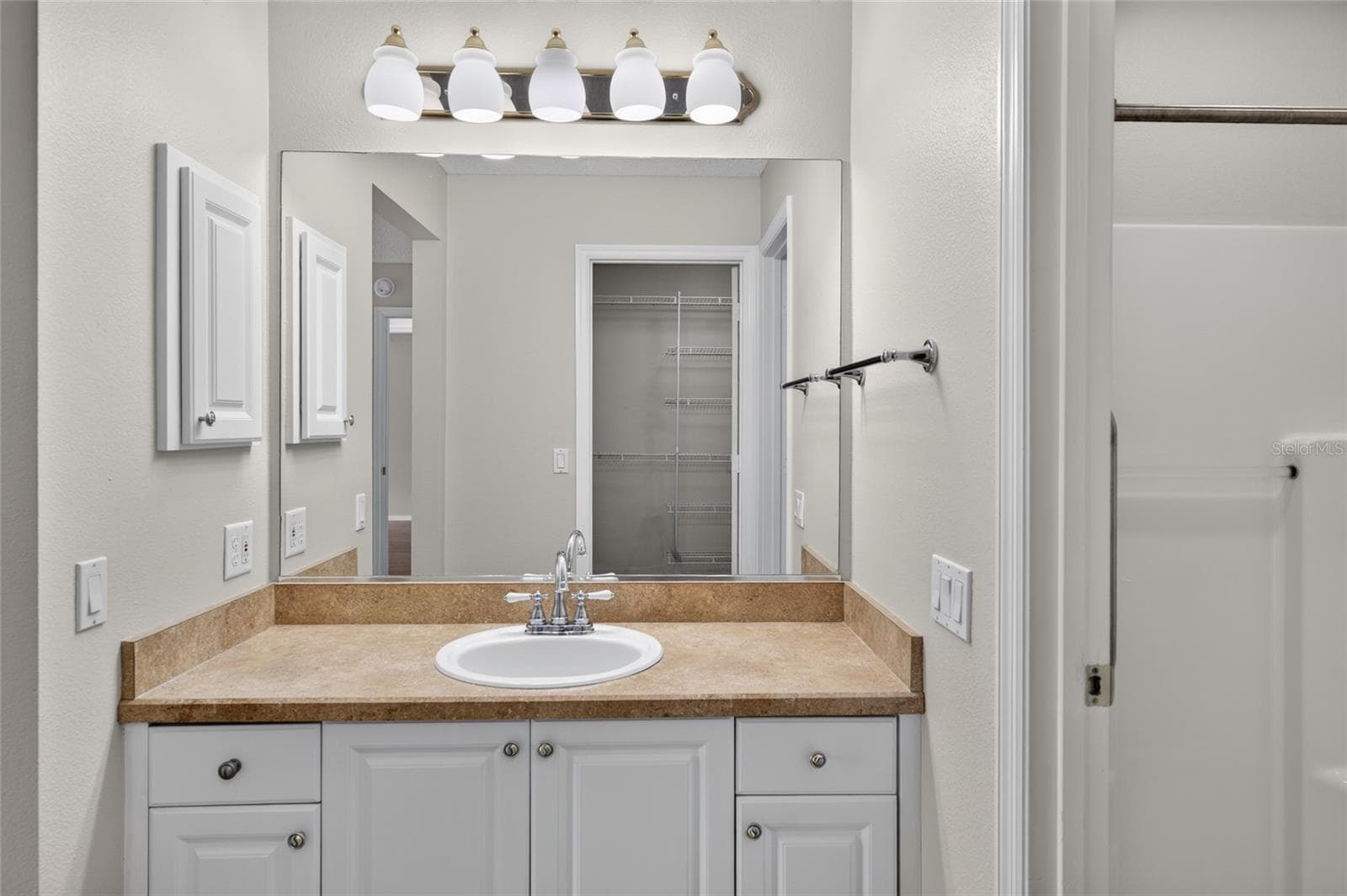 PRIMARY ENSUITE BATHROOM - View across the vanity toward the walk-in closet doorway (reflected in the mirror). A glimpse of the WALK-IN SHOWER is visible on R. - 2124 ESCOBAR AVE, THE VILLAGES
