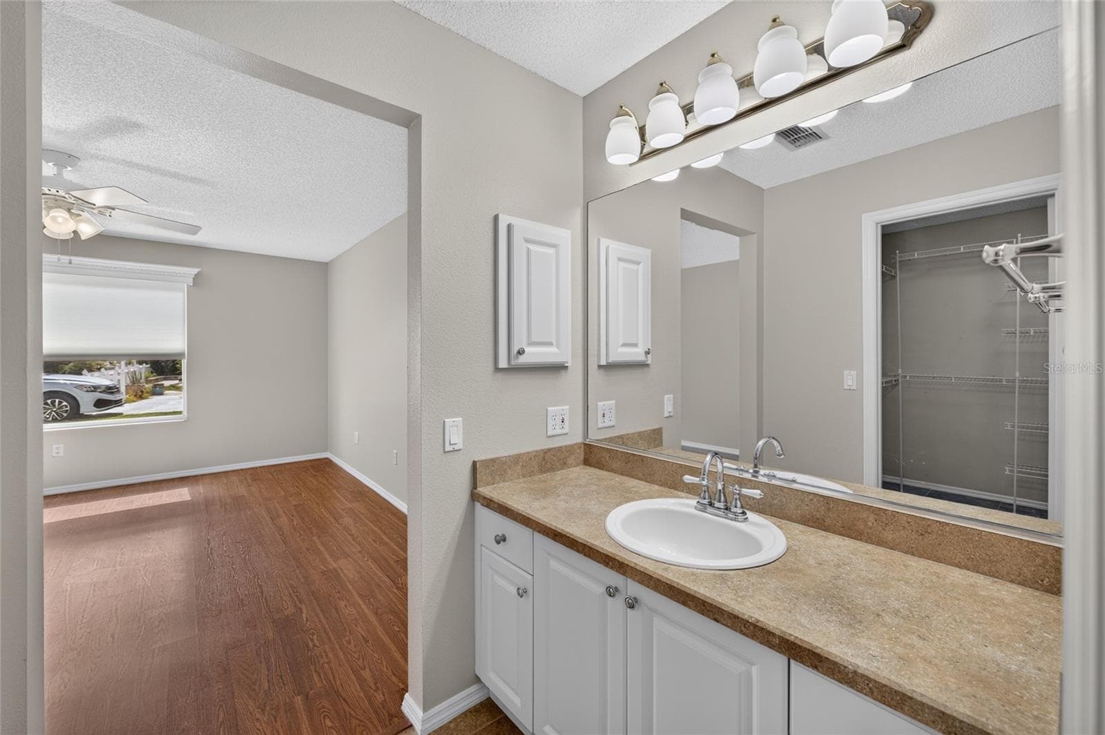 ENSUITE PRIMARY BATHROOM Vanity area - View from the single-sink vanity into the adjoining PRIMARY BEDROOM. - 2124 ESCOBAR AVE, THE VILLAGES