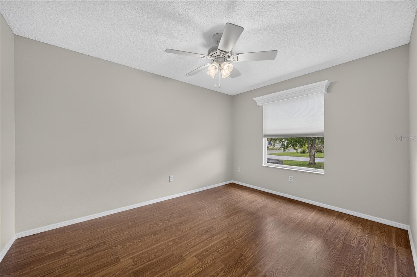 View of BEDROOM #2 from doorway - Shows large window with white wooden window cornice and ceiling fan with light. - 2124 ESCOBAR AVE, THE VILLAGES