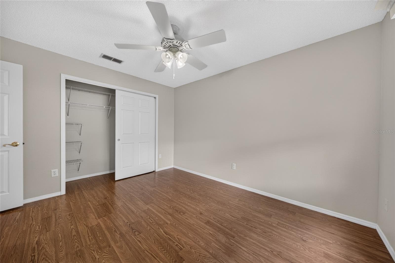 BEDROOM #2 - Open closet view reveals shelving and hanging space behind the double closet doors. - 2124 ESCOBAR AVE, THE VILLAGES