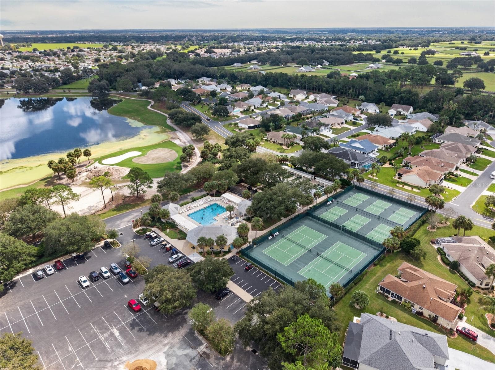 EL SANTIAGO RECREATION area / AERIAL - Overview of the community recreation grounds, with neighborhood homes and golf-course greens in the background. - 2124 ESCOBAR AVE, THE VILLAGES