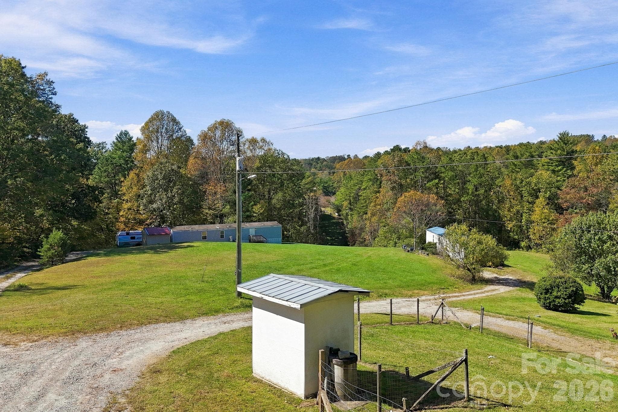 Wide-open grassy area with established gravel access and existing utility infrastructure, illustrating the property's functional layout. - 631 Union Hill Road, Hendersonville
