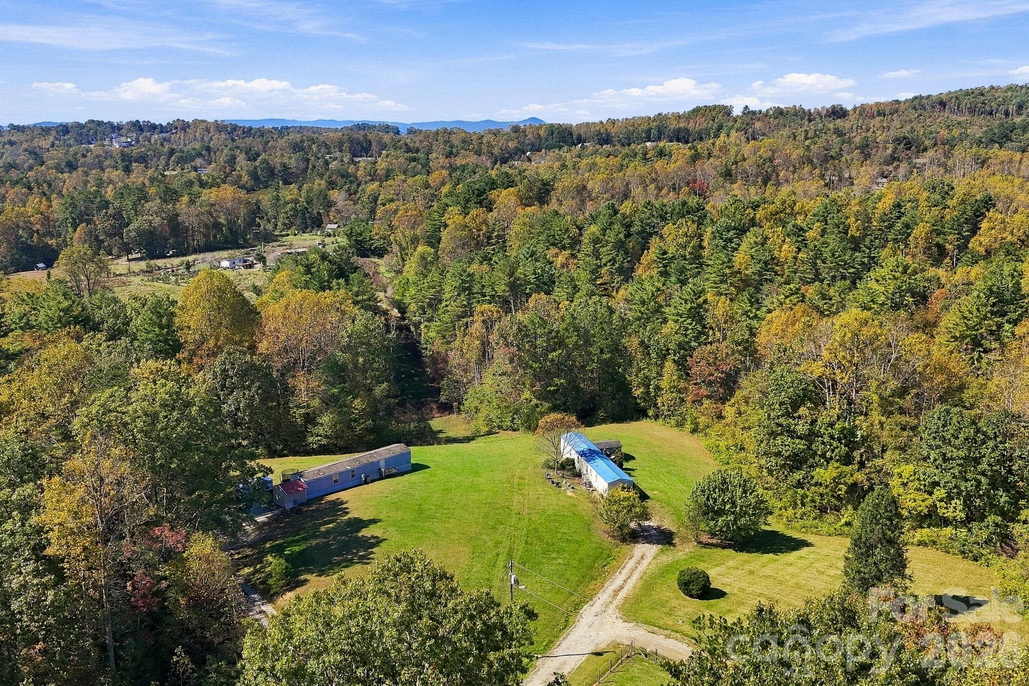 Beautiful aerial perspective captures open lawns, colorful hardwoods, and distant mountain scenery across the surrounding countryside. - 631 Union Hill Road, Hendersonville