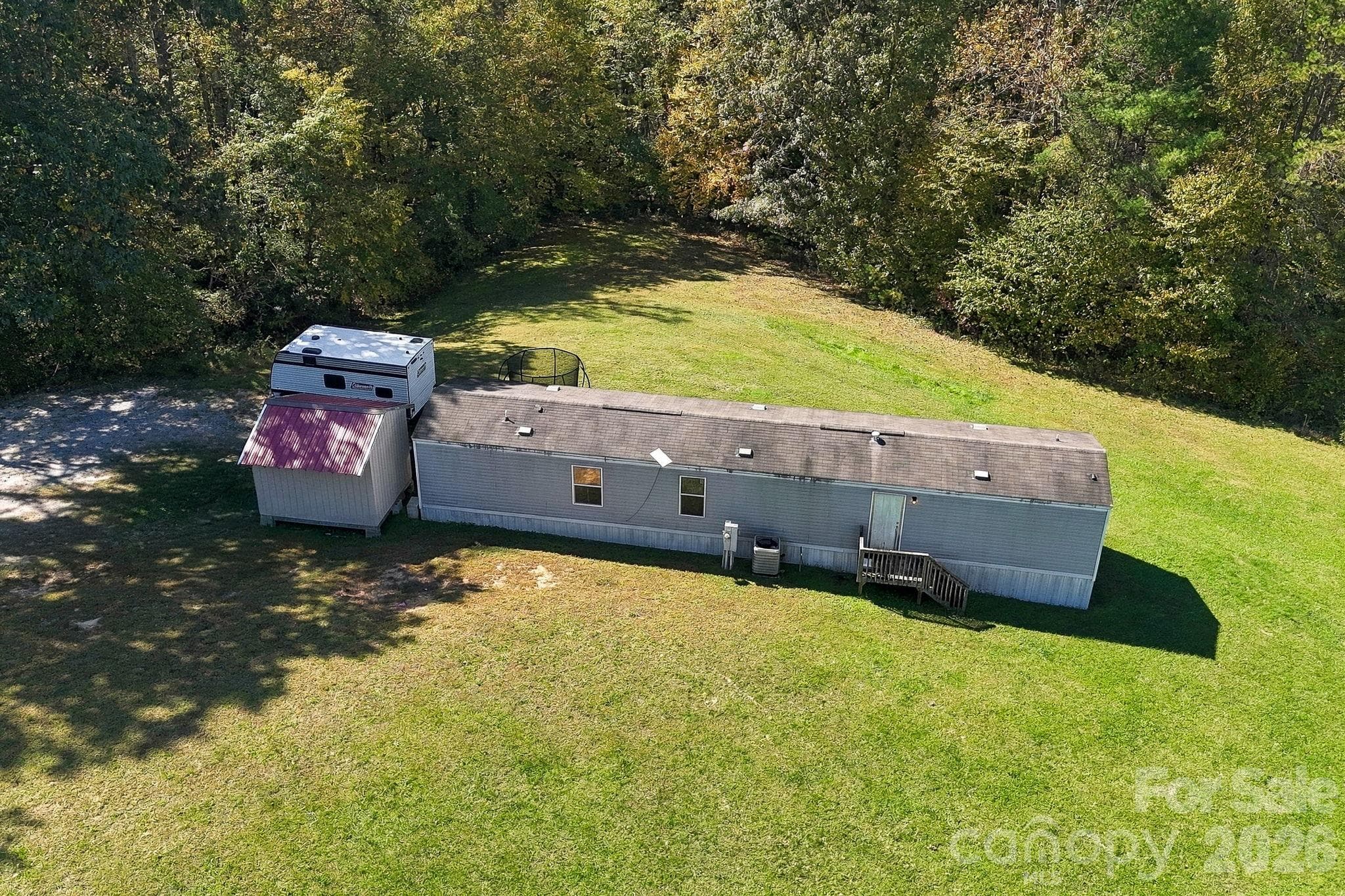 Spacious, gently sloping lawn surrounds this mobile home, with mature trees providing a natural backdrop and added privacy. - 631 Union Hill Road, Hendersonville