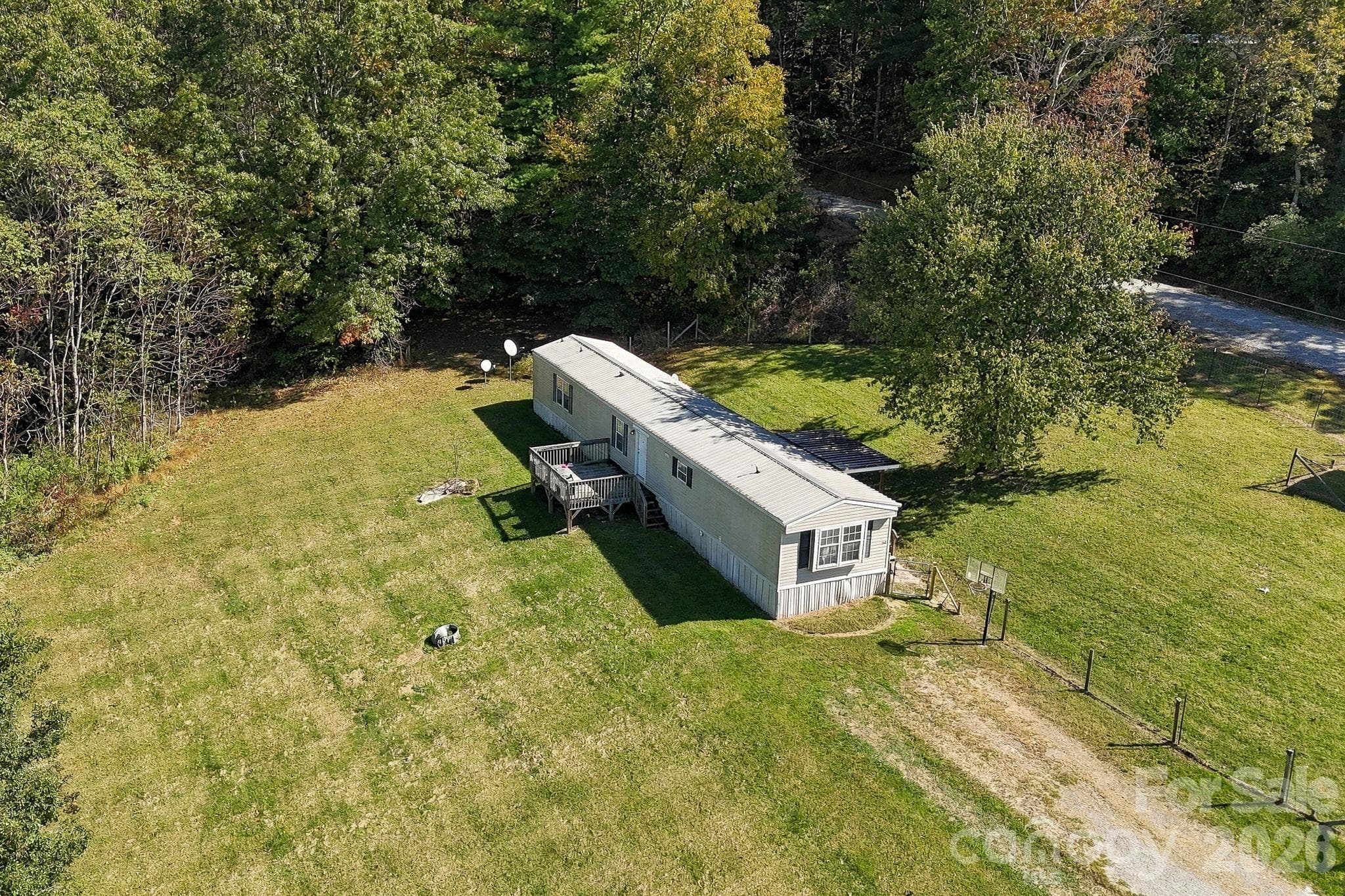 Aerial view showcasing the generous yard space, established driveway access, and peaceful wooded setting. - 631 Union Hill Road, Hendersonville