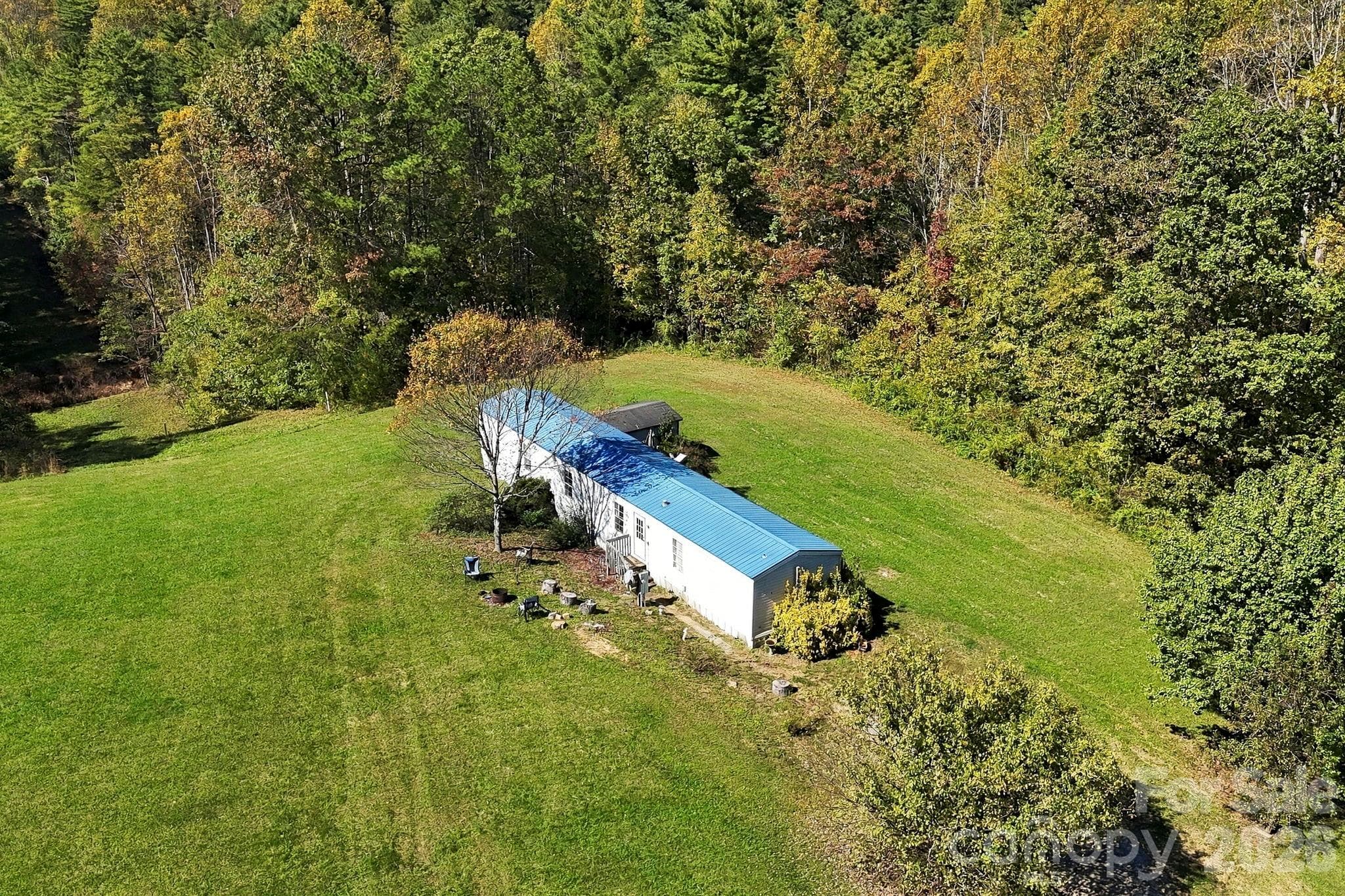 Beautifully maintained grassy clearing surrounded by mature hardwoods, highlighting the property's attractive topography. - 631 Union Hill Road, Hendersonville