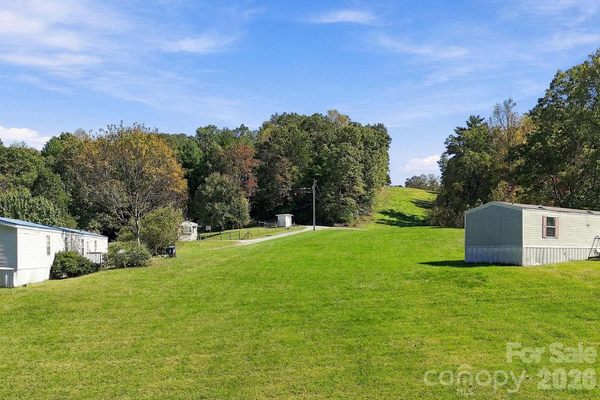 Expansive grassy clearing between existing residences highlights the property's exceptionally usable terrain and spacious setting. - 631 Union Hill Road, Hendersonville