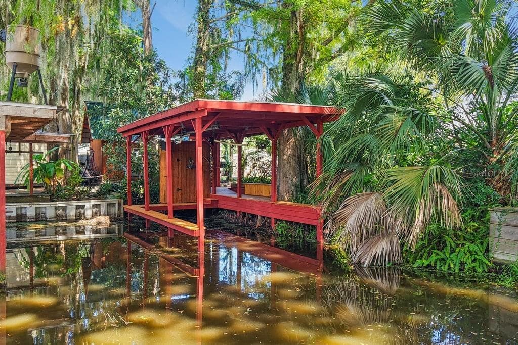 View of boathouse from the canal and many cypress trees - 30749 GLENN DR, TAVARES