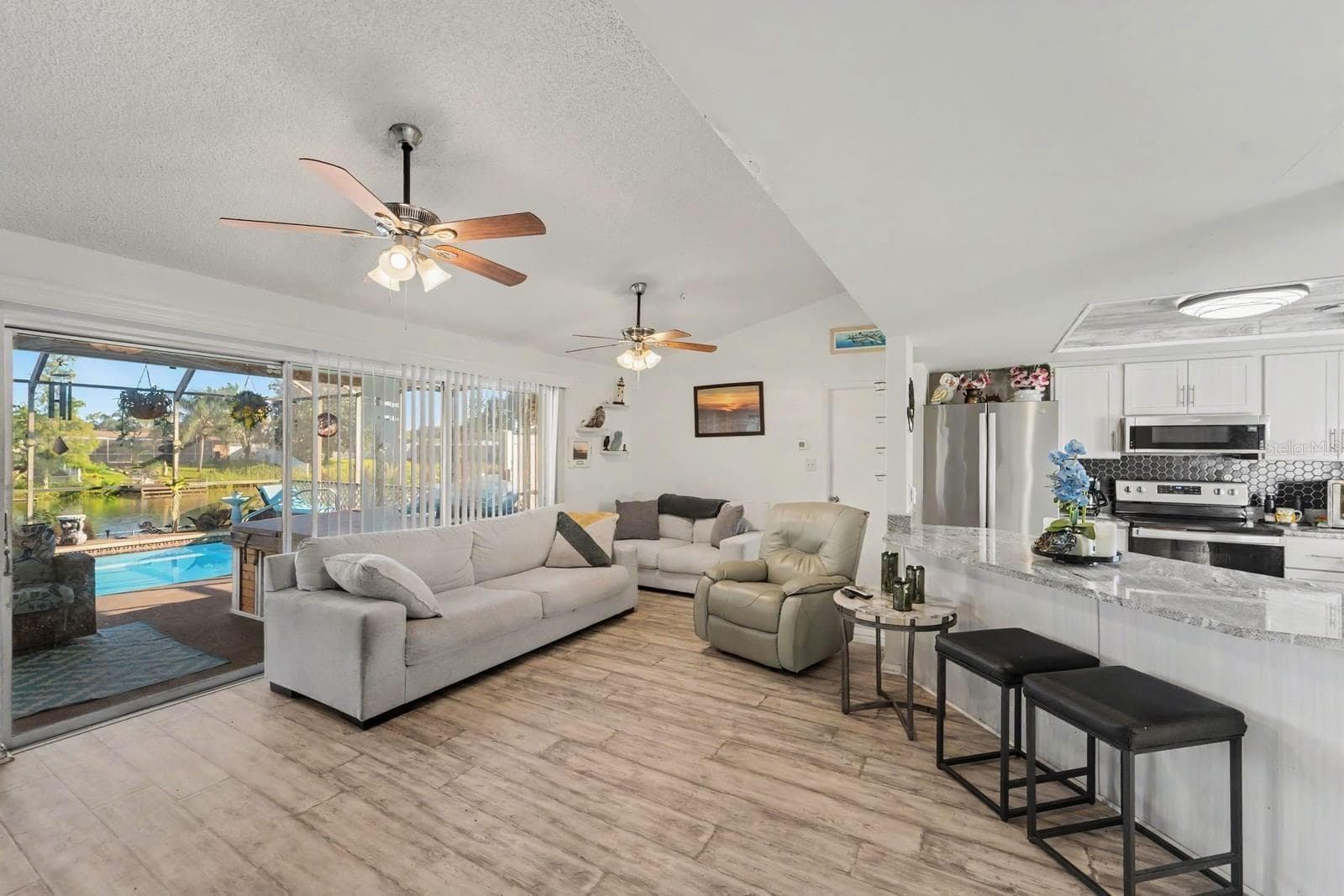 Open-concept living with pool view, modern kitchen, and ceiling fans - 8431 REDFIELD DR, PORT RICHEY