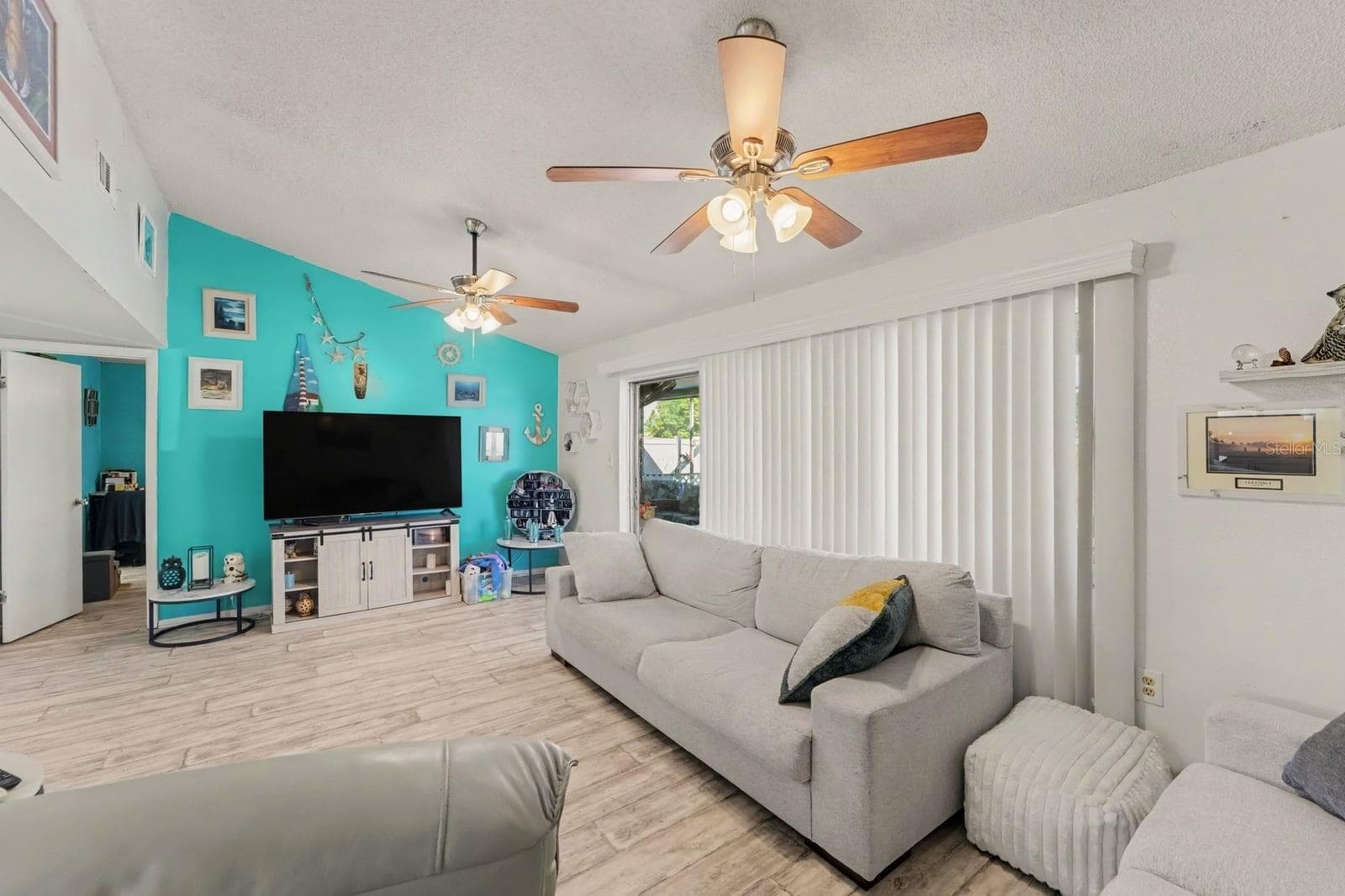 Spacious family room with turquoise accent wall and sliding glass doors - 8431 REDFIELD DR, PORT RICHEY