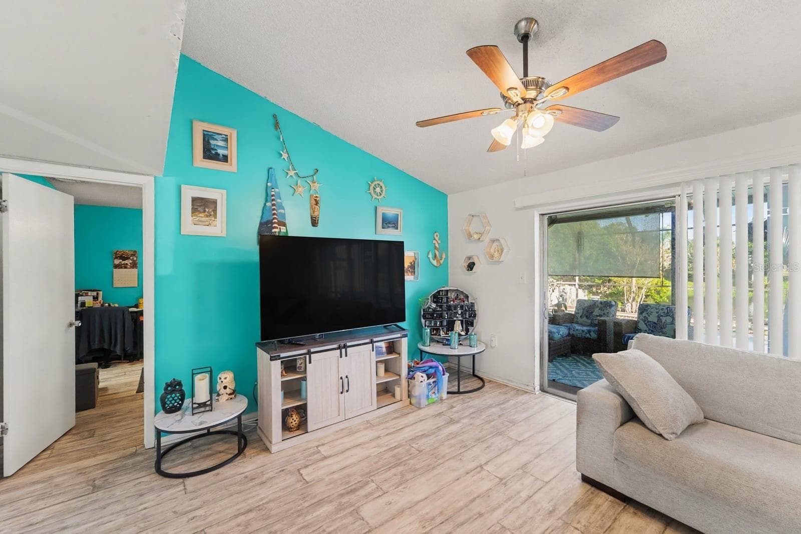 Bright media room with turquoise feature wall and sliding patio access - 8431 REDFIELD DR, PORT RICHEY