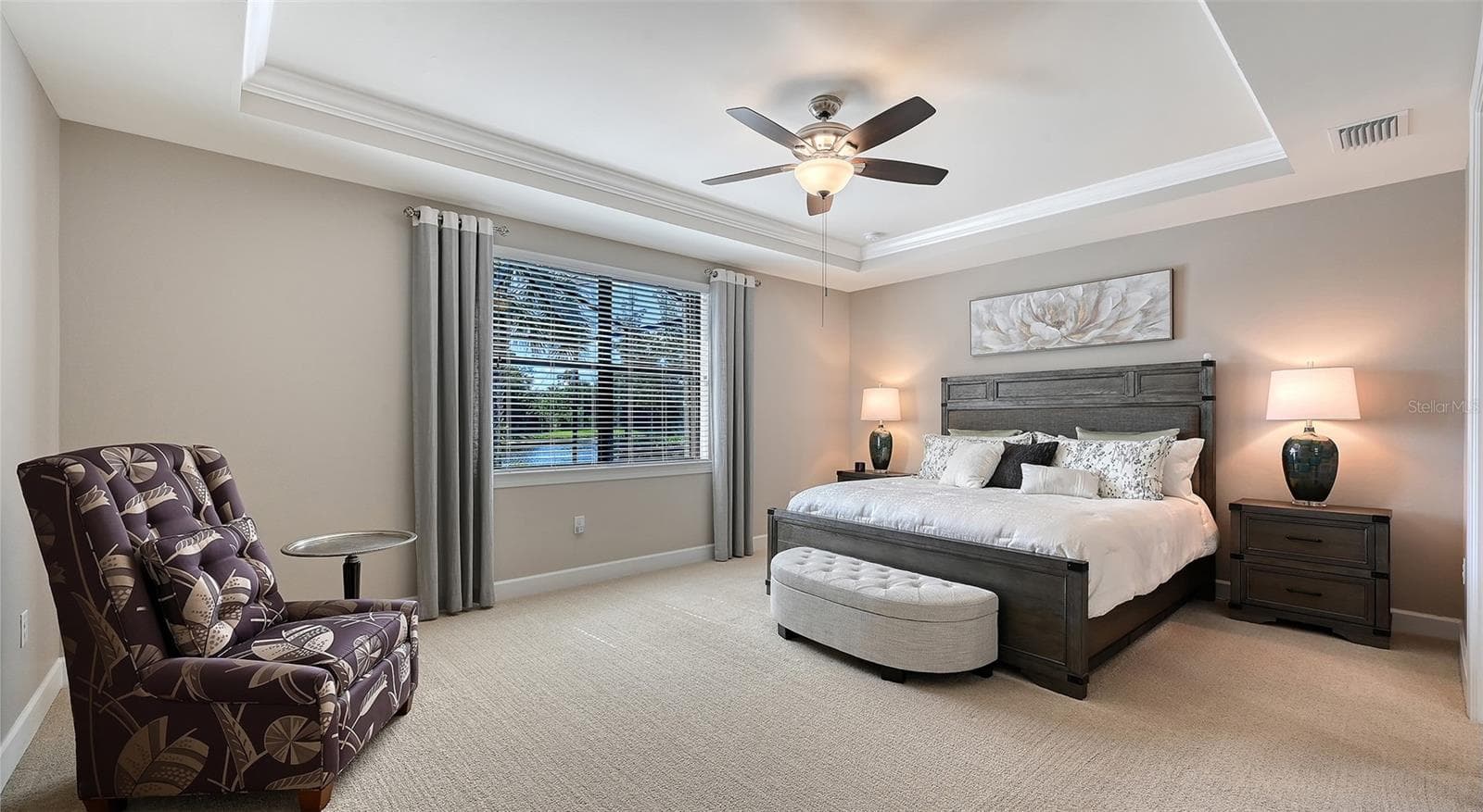 This spacious primary suite features an elegant tray ceiling and captivating views of the sparking pool and picturesque water beyond. - 6827 GOSPORT CV, BRADENTON