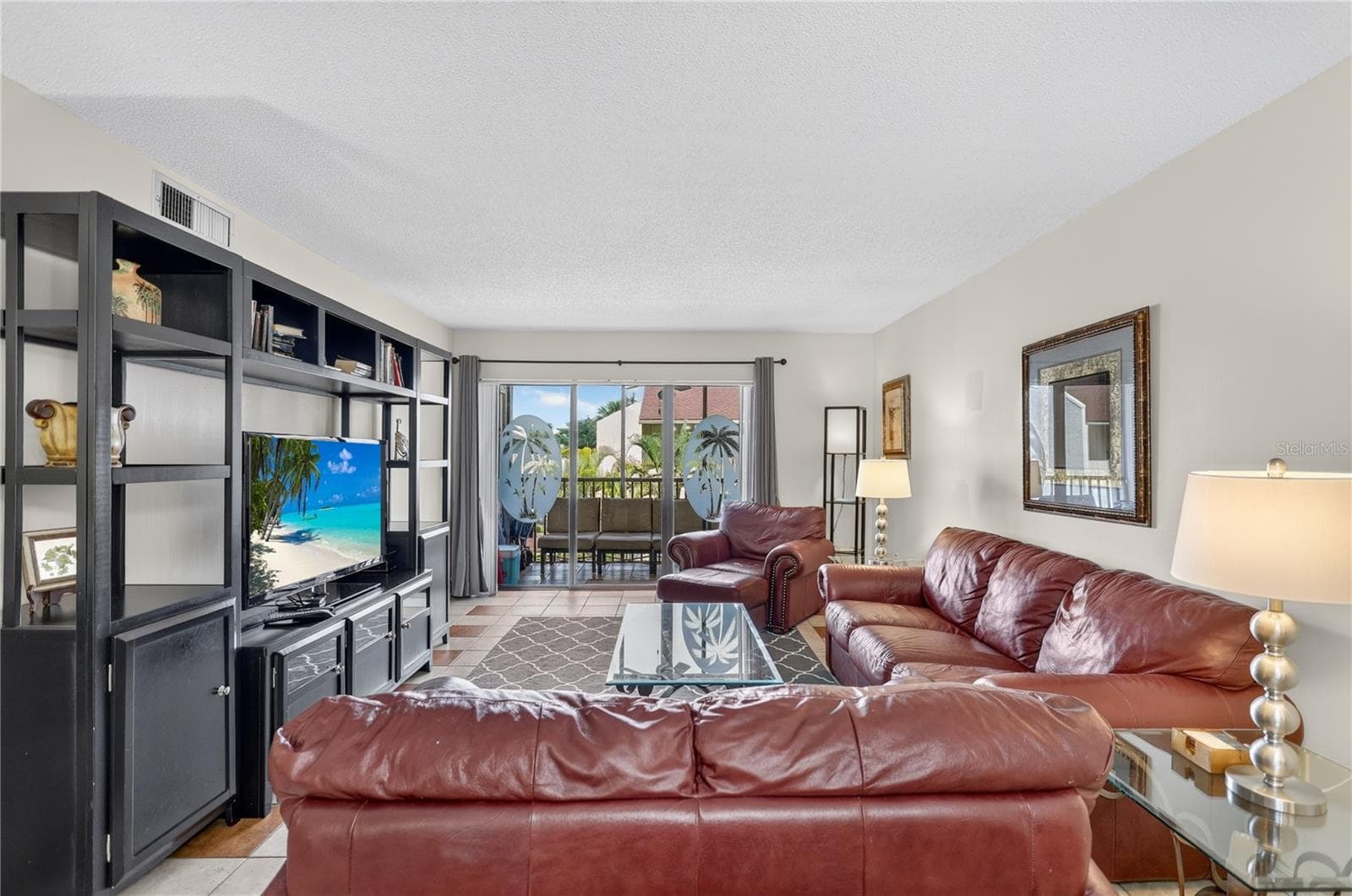 Spacious living room featuring sliding glass doors that open to a balcony overlooking the pool. - 6157 MIDNIGHT PASS RD #E53, SARASOTA