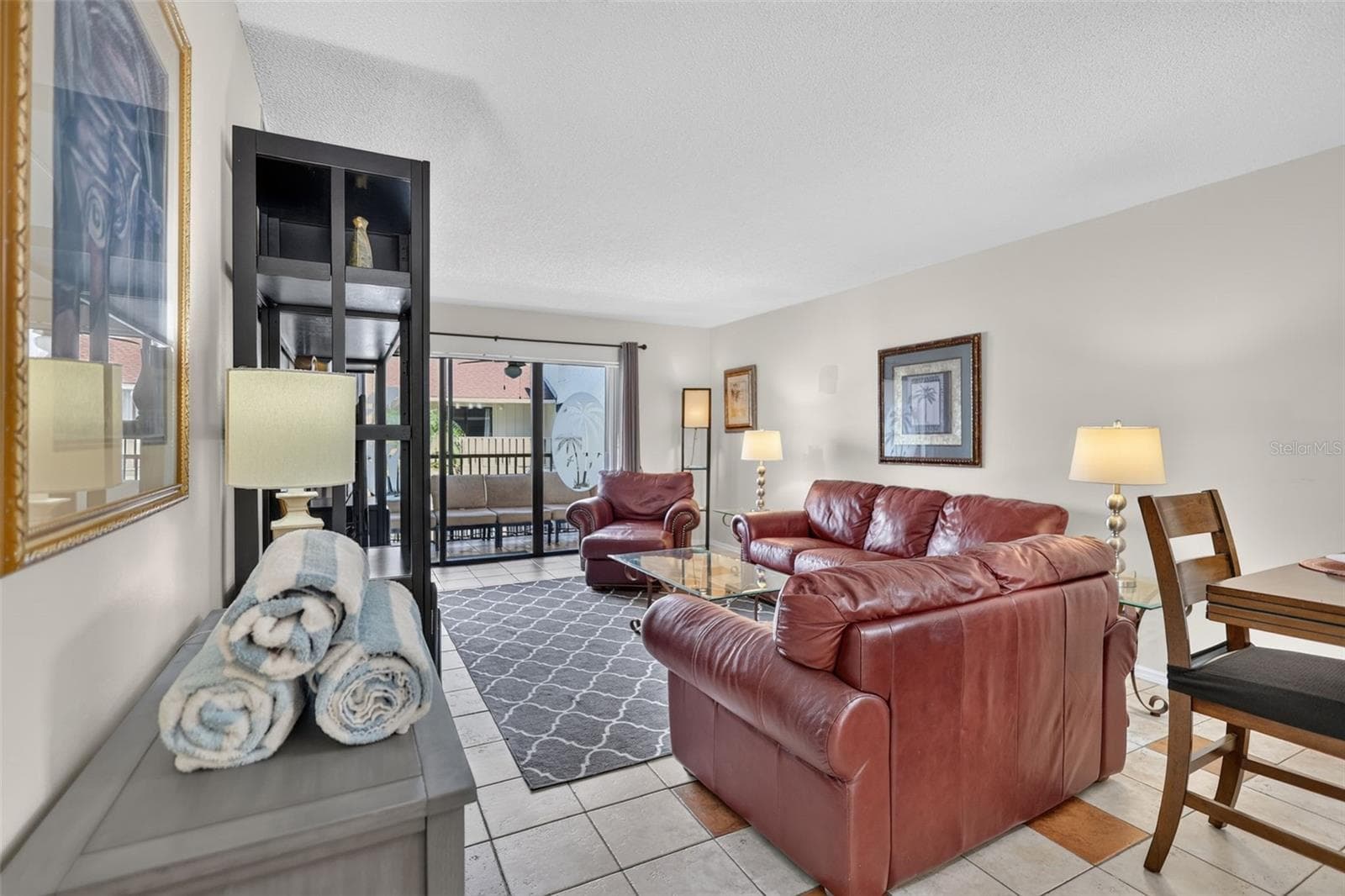 Spacious living room featuring sliding glass doors that open to a balcony overlooking the pool. - 6157 MIDNIGHT PASS RD #E53, SARASOTA