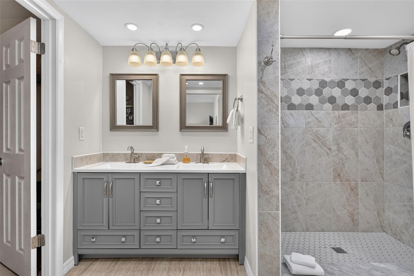 The primary bathroom features beautifully tiled walkin shower, dual sinks, dual mirrors, and generous lighting. - 6157 MIDNIGHT PASS RD #E53, SARASOTA