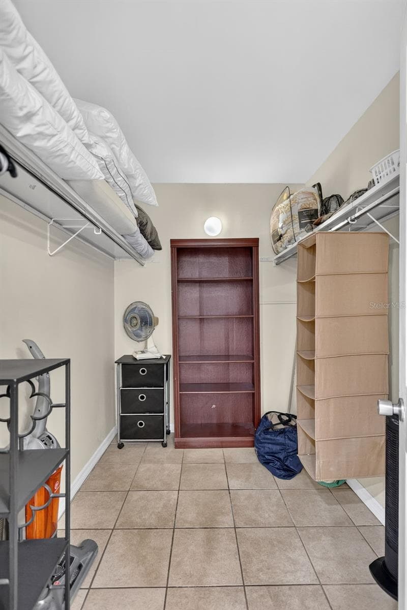 Walk-in closet with storage, located off the primary bathroom. - 6157 MIDNIGHT PASS RD #E53, SARASOTA