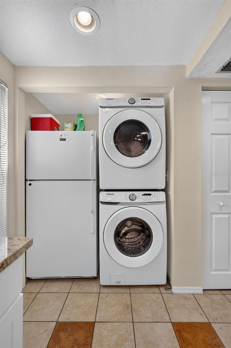This refrigerator and laundry area features a convenient stacked washer and dryer setup. - 6157 MIDNIGHT PASS RD #E53, SARASOTA