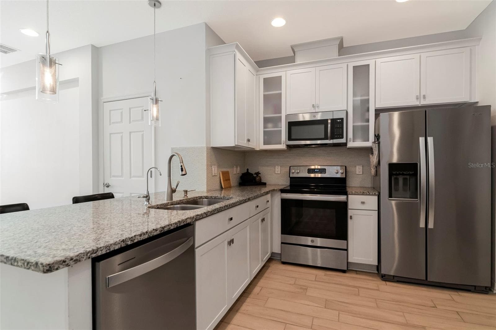 Stylish kitchen with white cabinetry, granite countertops, and stainless steel appliances. - 2455 GOLDEN PASTURE CIR, CLEARWATER