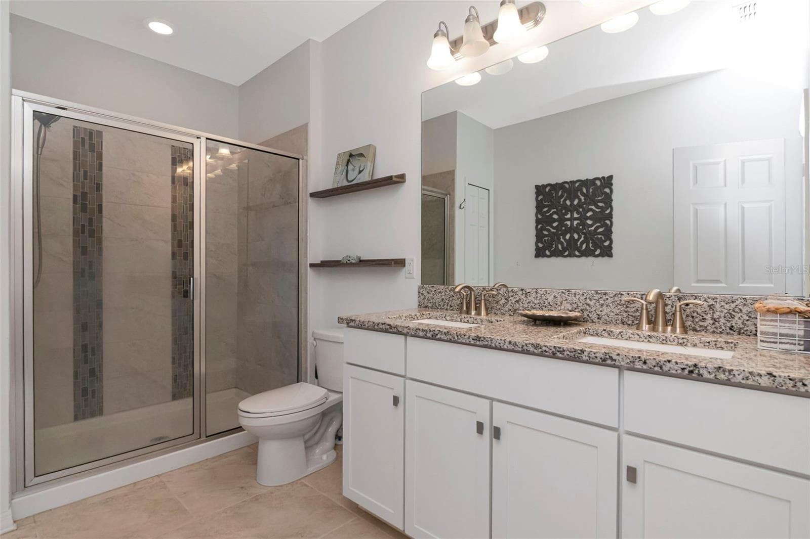 Primary en-suite bathroom featuring granite countertops and a beautifully tiled walk-in shower. - 2455 GOLDEN PASTURE CIR, CLEARWATER