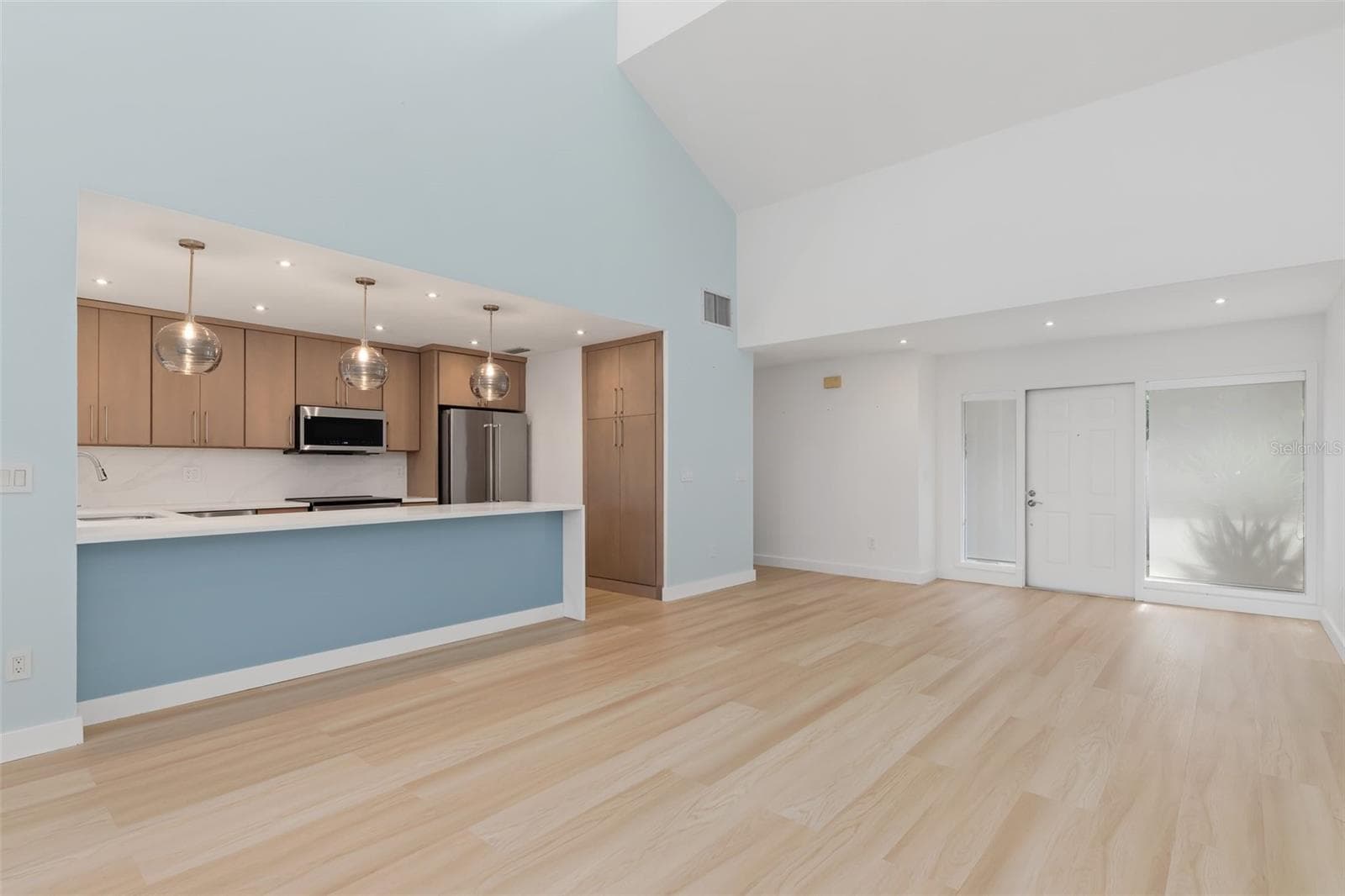 Great room unfurnished. Kitchen breakfast bar with lighted blue glass face, modern cabinetry and pendant lighting. - 5021 SAN ROCCO CT, PUNTA GORDA