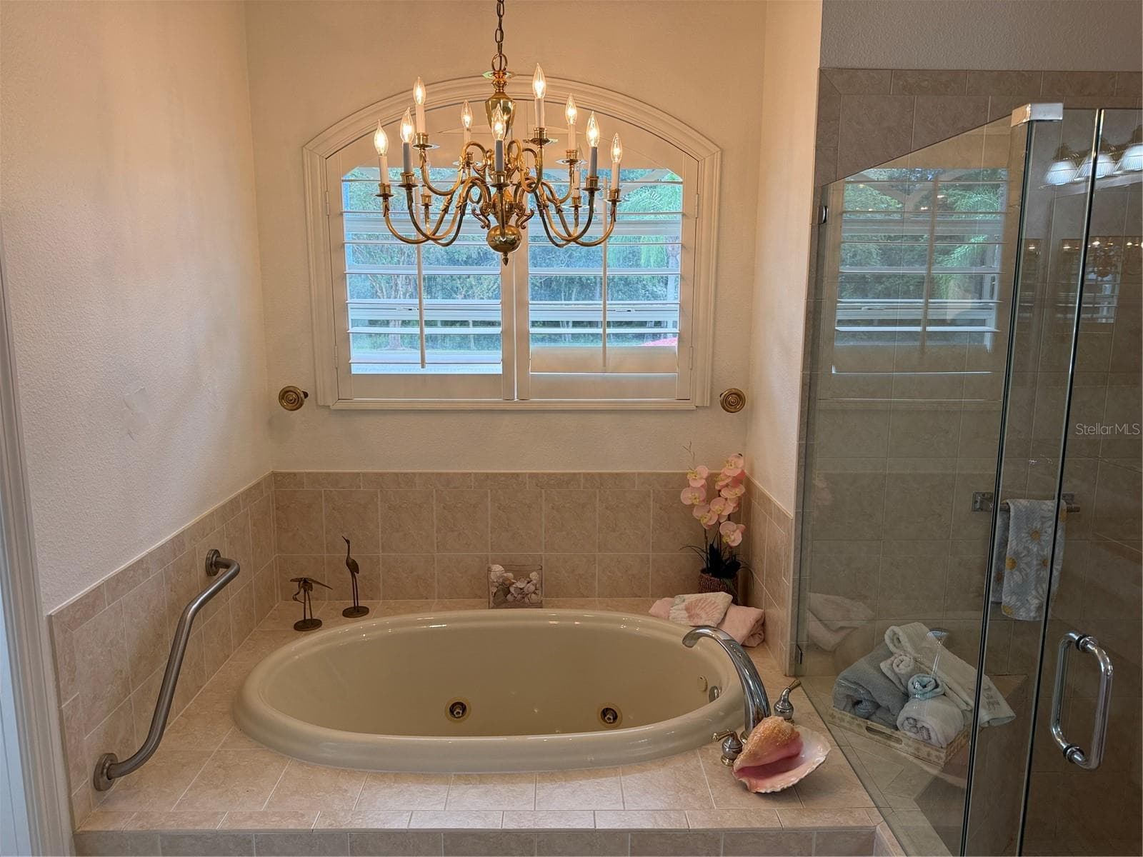 Jetted tub, chandelier, and plantation shutter in primary bathroom - 2311 OASIS DR, LAND O LAKES