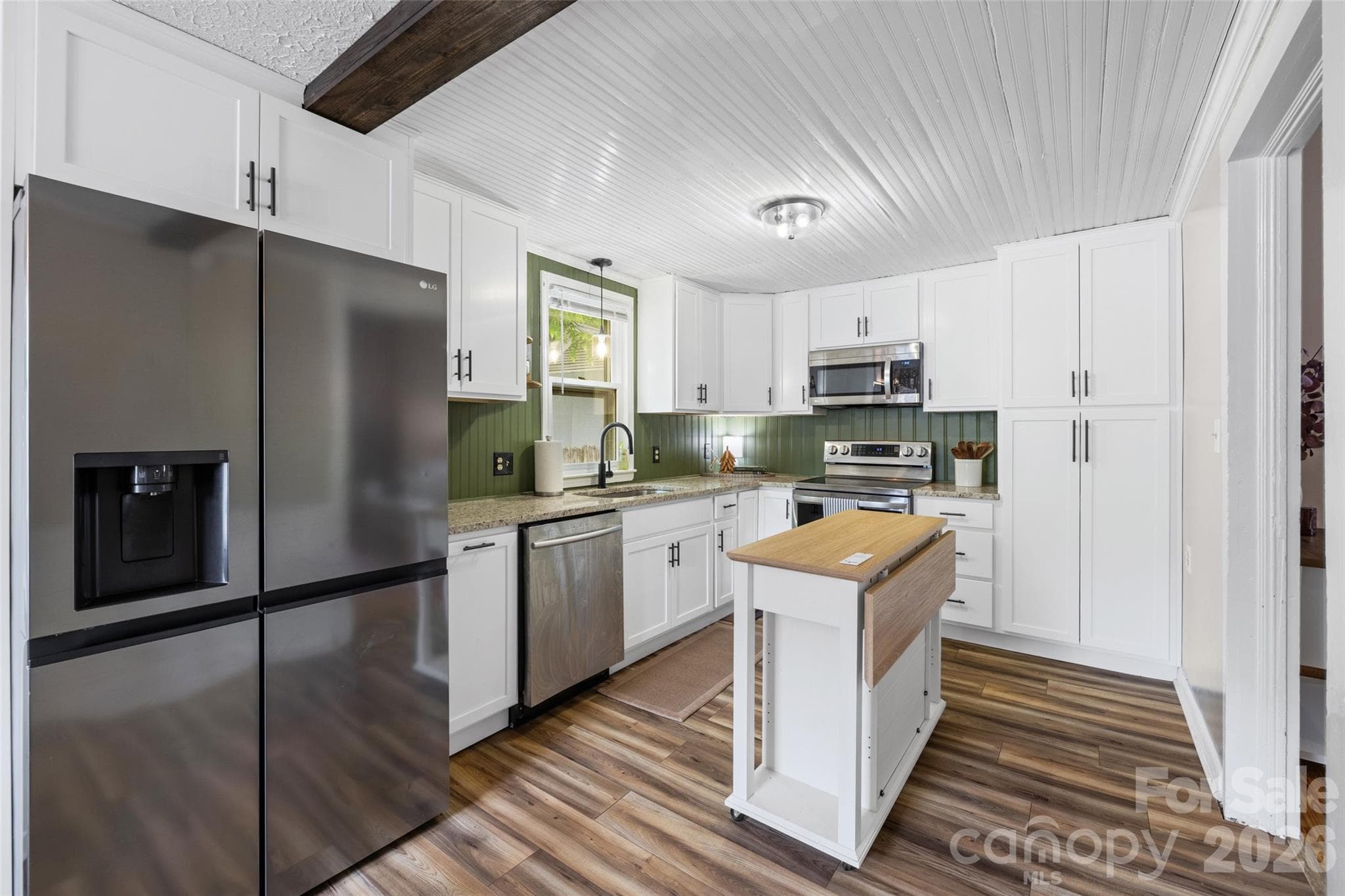 Beautifully remodeled kitchen featuring new white cabinetry, granite countertops, stainless steel appliances, and a center island. - 231 E Jefferson Street, York
