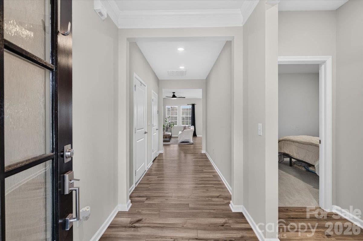 Bright and welcoming hallway featuring gorgeous continuous flooring and modern dark-framed glass doors. - 155 White Apple Way, Statesville