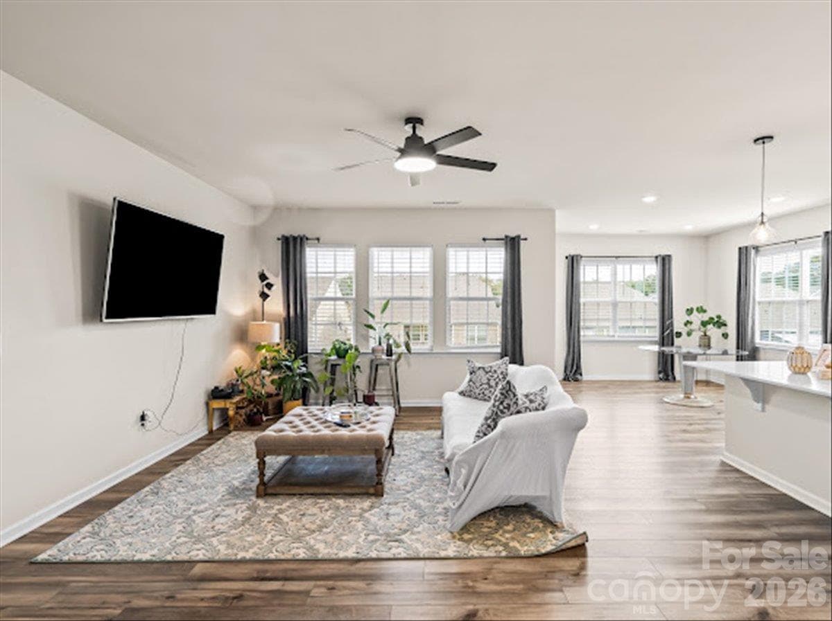 Sun-drenched living room offering plenty of natural light, a ceiling fan, and abundant space for relaxing or entertaining. - 155 White Apple Way, Statesville
