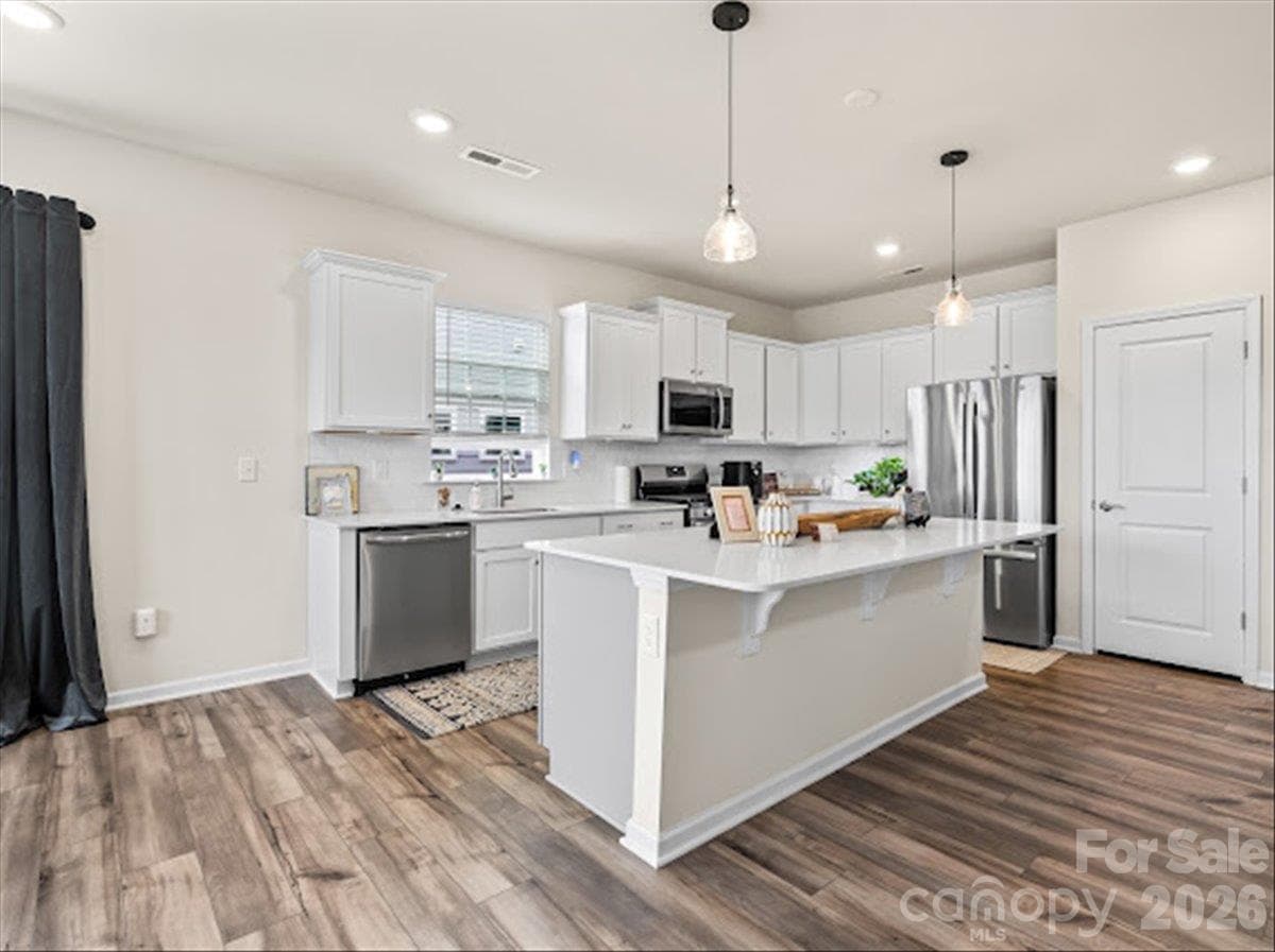 Stunning modern kitchen featuring crisp white cabinetry, sleek stainless steel appliances, and a beautiful center island. - 155 White Apple Way, Statesville