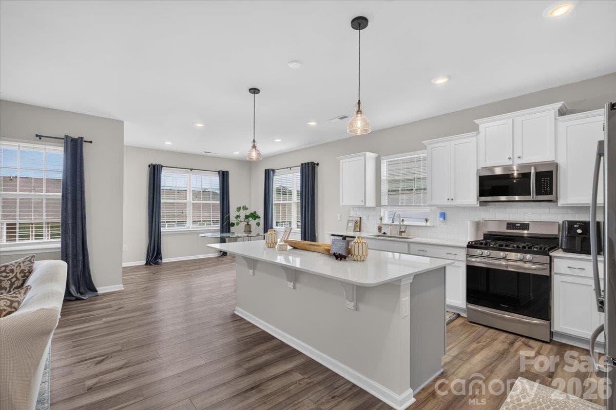 Perfect open-concept layout showcasing the flow from the expansive kitchen island directly into the bright, airy living space. - 155 White Apple Way, Statesville