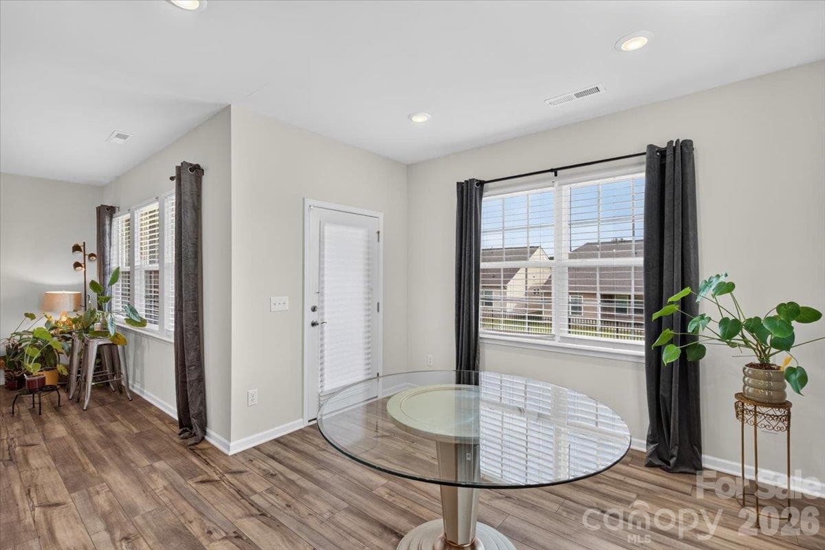 Bright and elegant dining area featuring large windows that flood the space with natural light and stylish continuous flooring. - 155 White Apple Way, Statesville