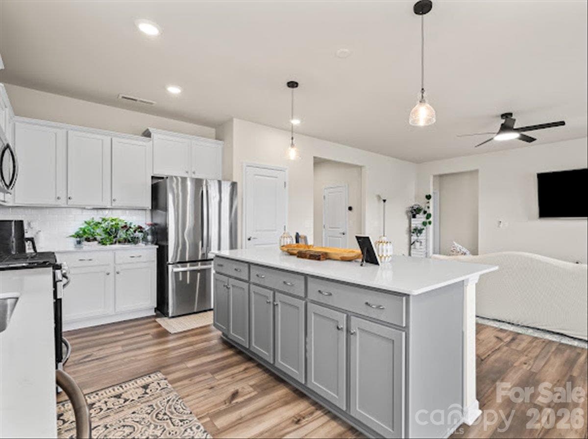 Another angle of the gorgeous kitchen, highlighting the sleek cabinetry, modern stainless appliances, and chic pendant lights over the island. - 155 White Apple Way, Statesville
