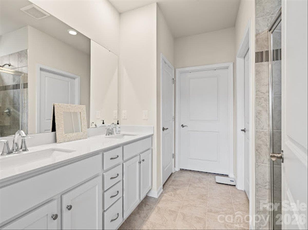 Bright and pristine bathroom featuring an elegant dual vanity with ample storage and crisp white cabinetry. - 155 White Apple Way, Statesville