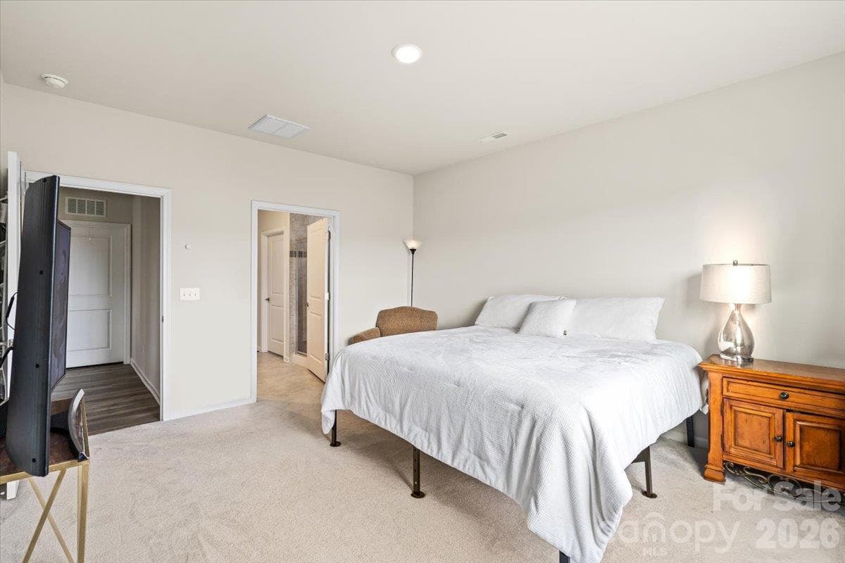 Spacious primary bedroom retreat featuring plush carpeting, elegant window treatments, and plenty of natural light. - 155 White Apple Way, Statesville